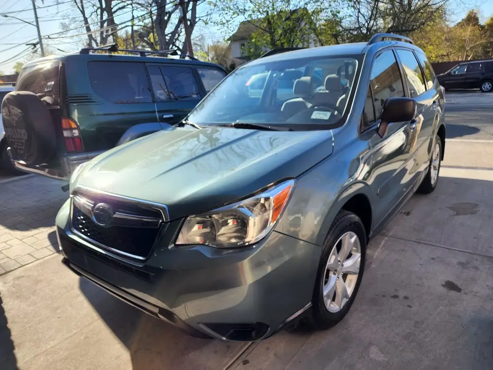 Green Subaru Forester SUV parked on a paved lot after its repair