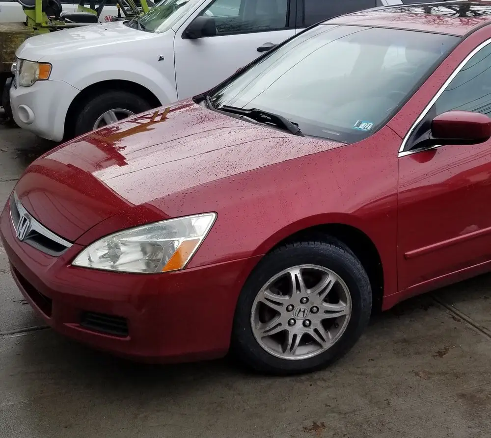 Red Honda Accord sedan parked on the shop's lot after its repair
