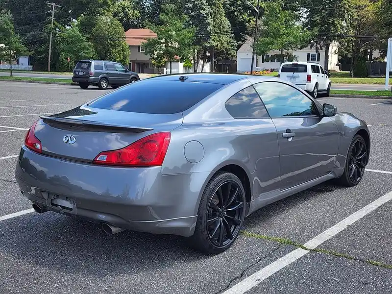 Silver Infiniti coupe with black wheels parked in a paved lot