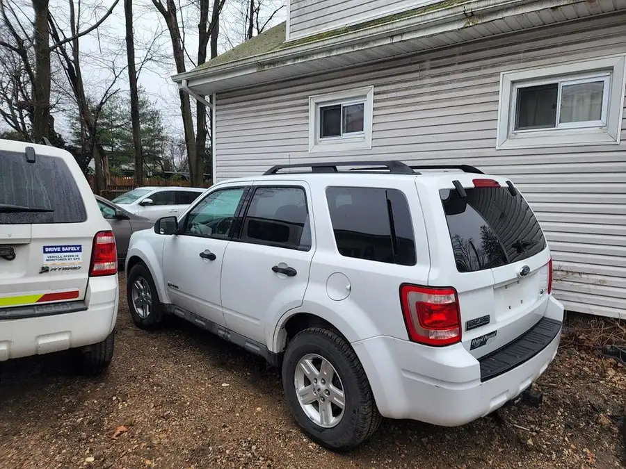 White Ford Escape SUV parked beside the shop's white-sided building