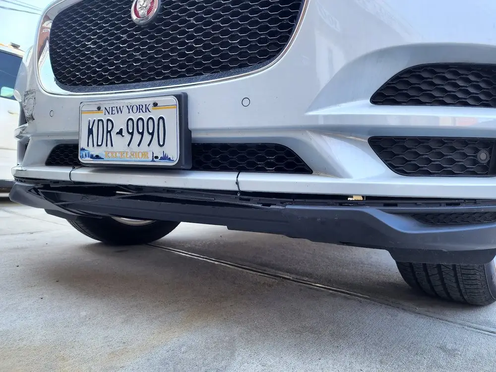 Close view of a white Jaguar SUV's front bumper, lower grille and air vents